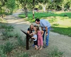 A young family gathers around a storybook panel at Granite Creek Park.